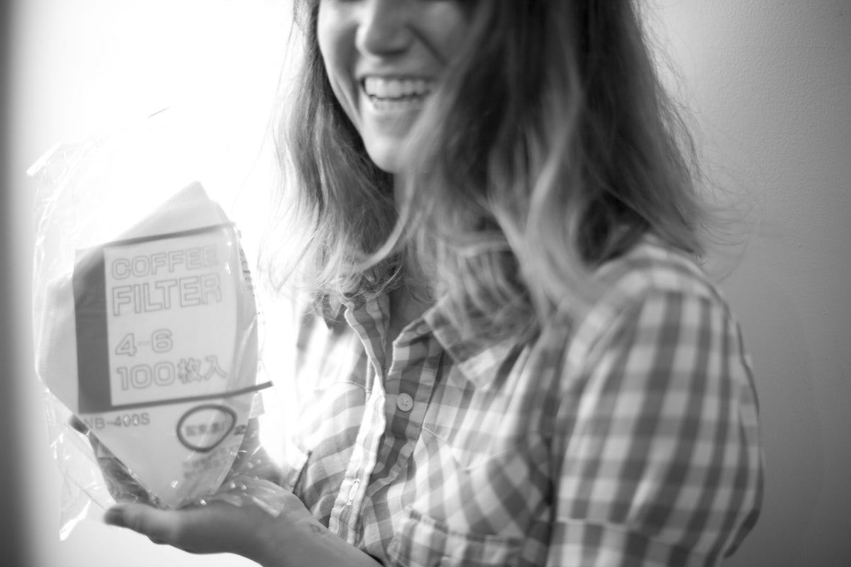 A woman smiling while holding a package of Bonmac #4 White Paper Filters.