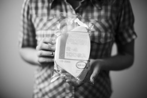 Person holding a plastic-wrapped package of cone-shaped white Bonmac #2 White Paper Filters.