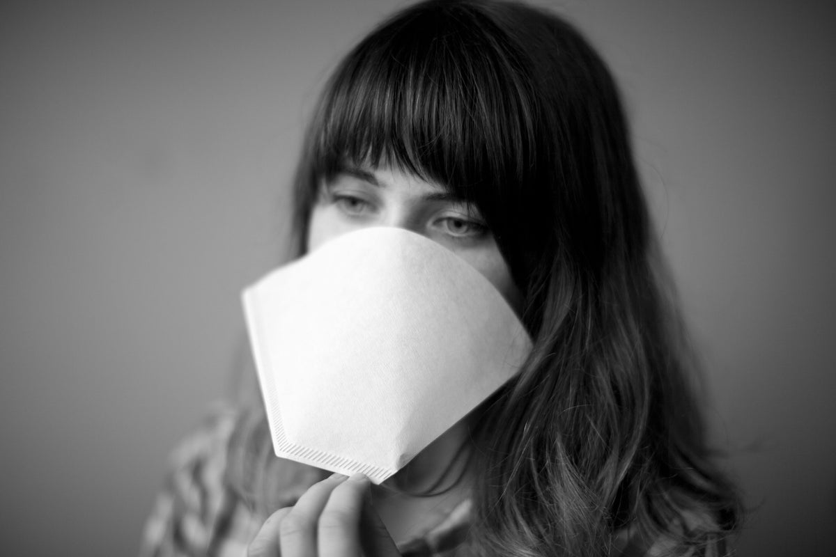A person holds a white conical Bonmac #4 White Paper Filters in front of their face.