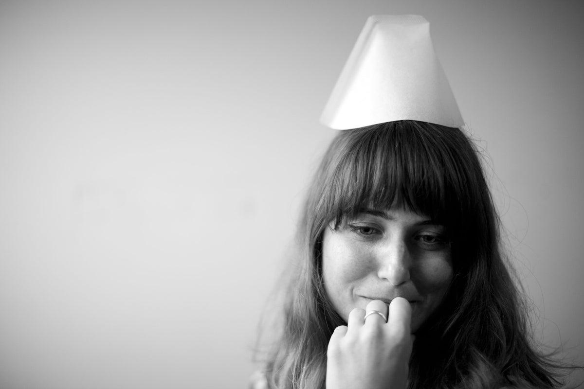 A woman with a white, cone-shaped Bonmac #2 White Paper Filters coffee filter balanced on top of her head.