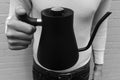 A person holds a black Fellow Stagg Stove Top Pour Over Kettle with a thermometer on the lid.
