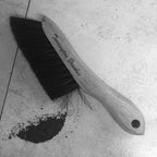 Torrington wood counter brush with dark bristles lying on a tiled surface next to a small pile of debris.